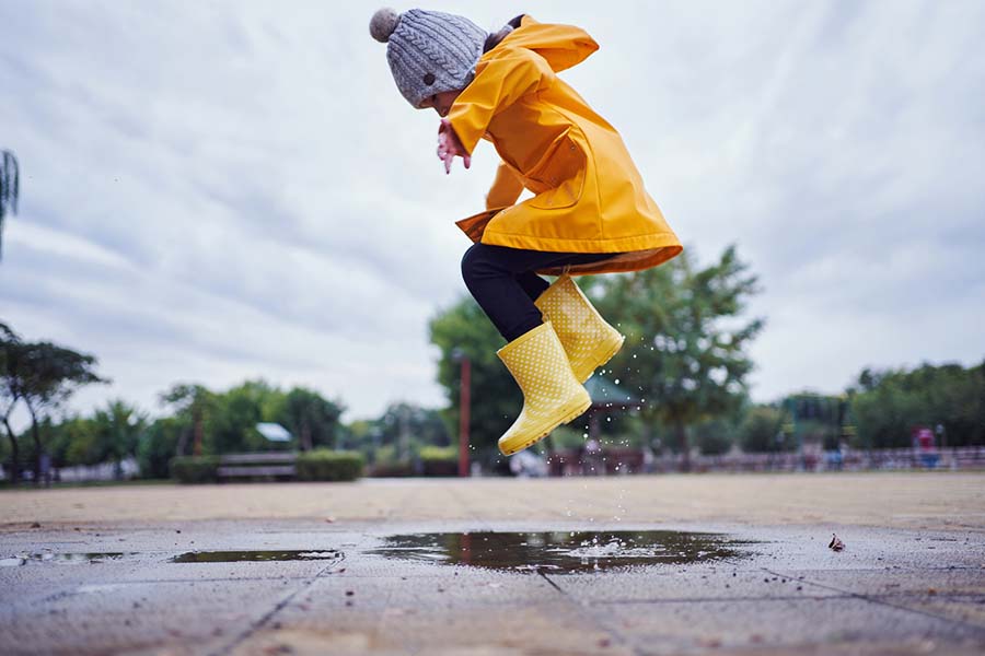 Happy child jumping in puddles to symbolise happy, healthy communities